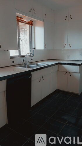 A kitchen with white cabinets and black countertops.