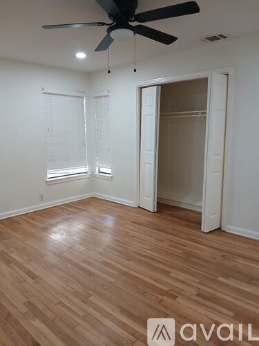 A room with a ceiling fan and wooden flooring.