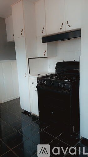 A black stove in a kitchen with white cabinets.