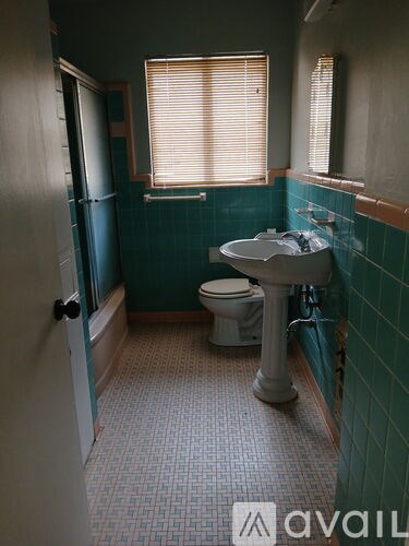 A bathroom with a toilet, sink, and a window with blinds.