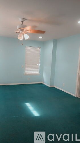 A room with a ceiling fan and a window with blinds.