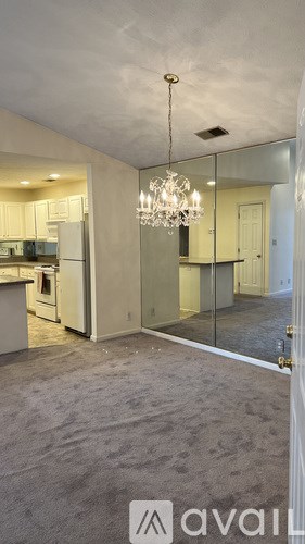 A modern kitchen with a chandelier and a view of the dining area.