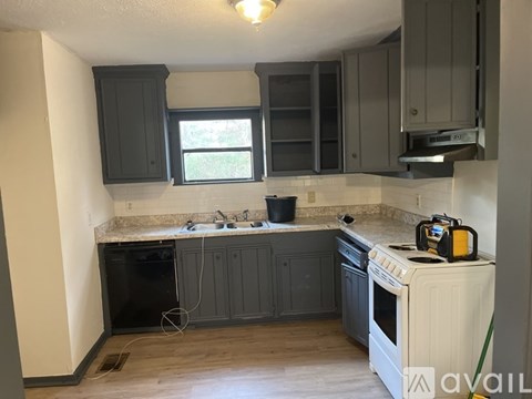 A kitchen with a white stove top oven and black cabinets.