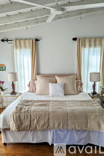 A bed with a beige comforter and pillows is in the image.