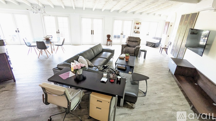 A living room with a black sofa and a black coffee table with a vase of flowers on it.