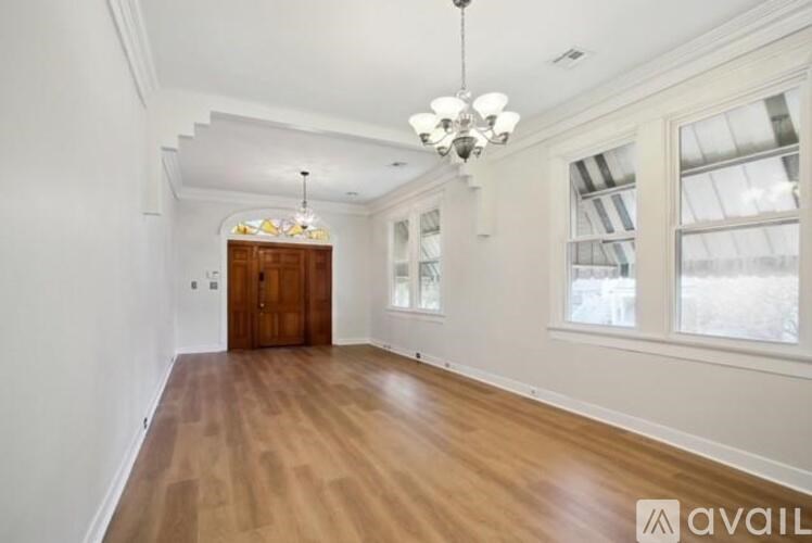 A room with wooden floors and a chandelier hanging from the ceiling.