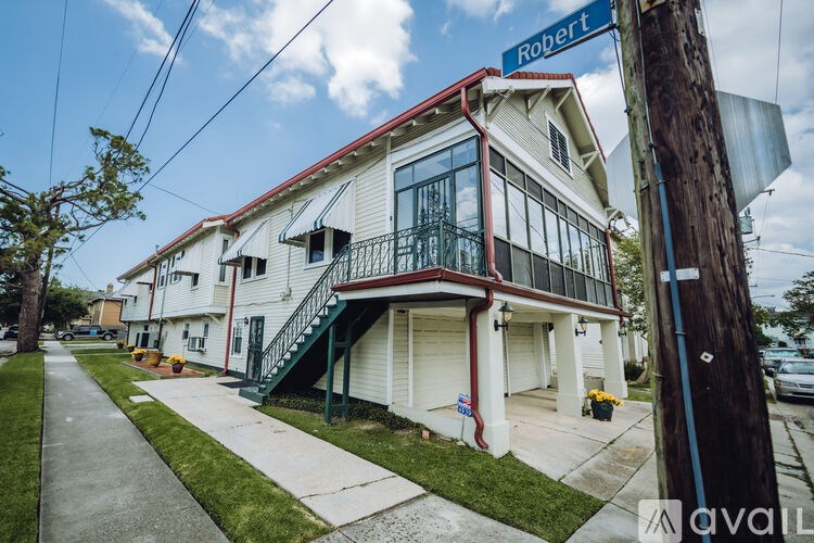 A white two-story building with a red roof and a balcony on the second floor.