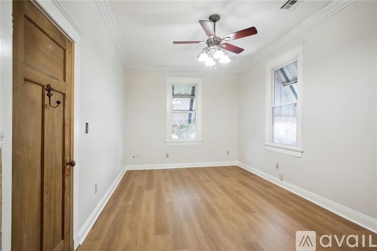 A room with a ceiling fan and wooden flooring.