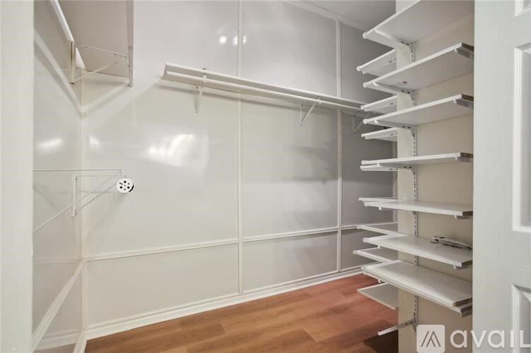 A white walk-in closet with shelves and a door.