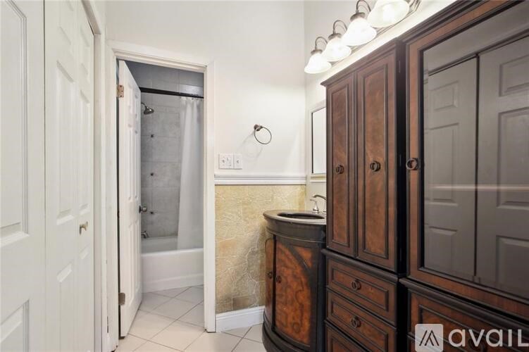 A bathroom with a shower, sink, and wooden cabinets.