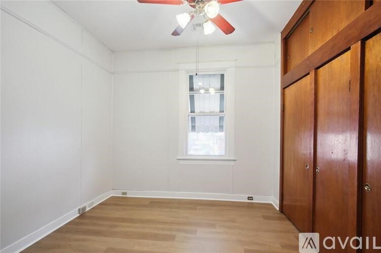 A room with a ceiling fan and a window with a wooden door on the side.
