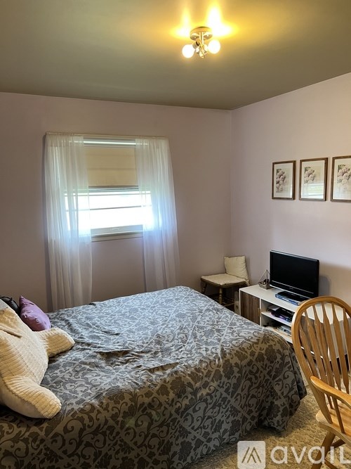 A bedroom with a bed, chair, and television.