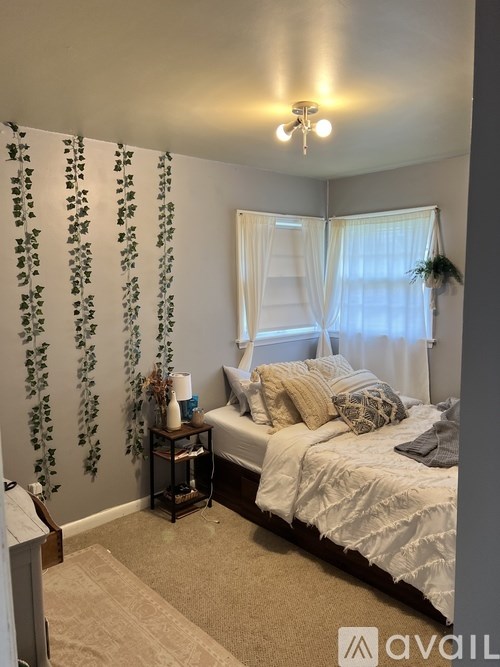 A bedroom with a bed, nightstand, and a wall decorated with greenery.