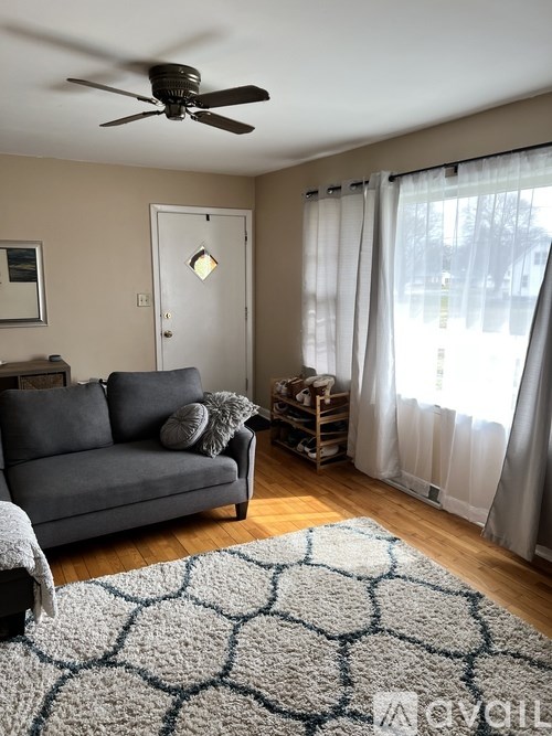 A living room with a grey couch and a ceiling fan.