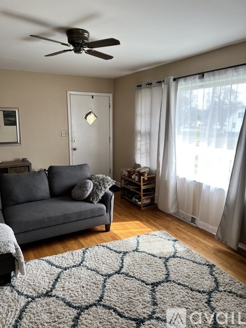 A living room with a grey couch and a ceiling fan.