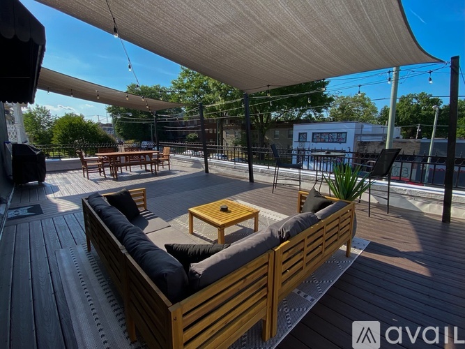 A wooden deck with a sofa and a coffee table under a white canopy.