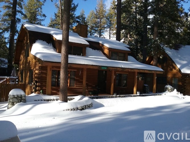 A wooden house with snow on the roof and ground.