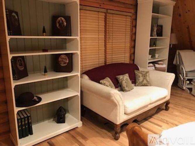 A white shelf with a hat on it sits next to a white couch.