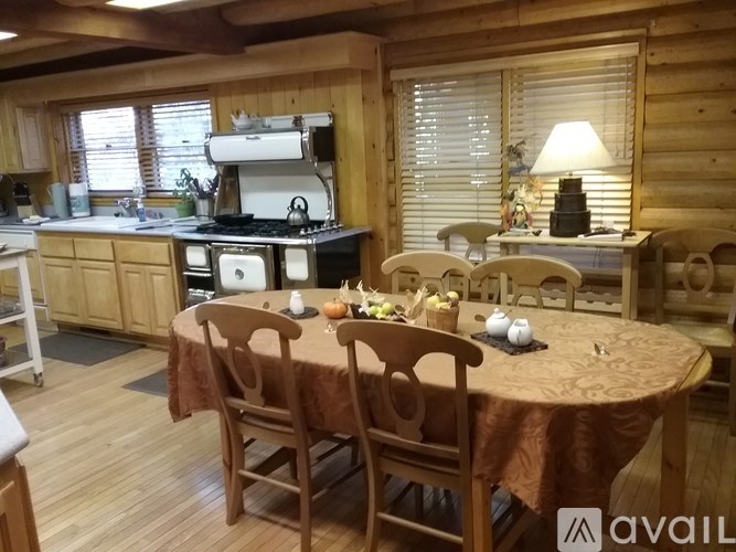 A wooden table with chairs and a brown tablecloth in a kitchen.