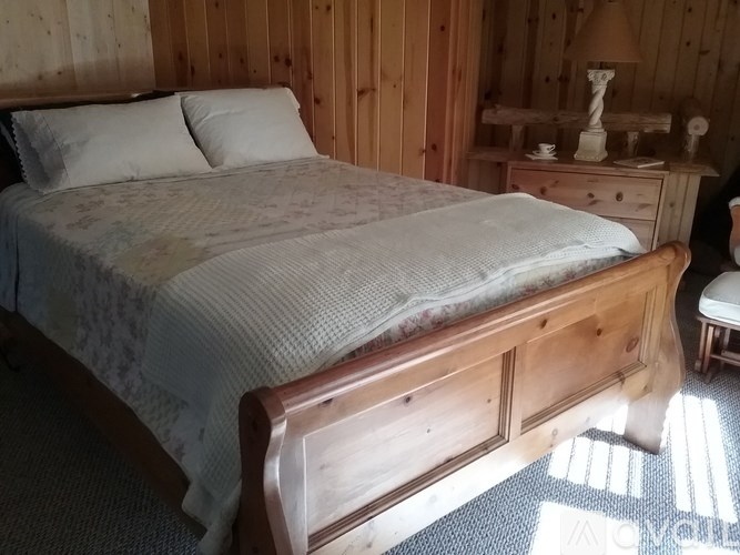 A bed with a wooden headboard and footboard sits in a room with wooden walls.