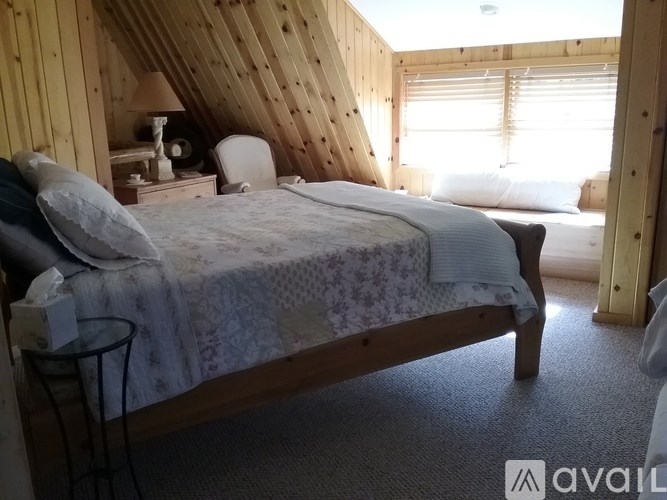 A bedroom with a bed, nightstand, and window.