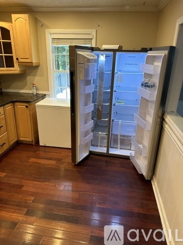 A kitchen with a refrigerator and wooden floors.