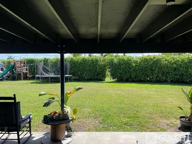 A patio with a table, chairs, and a potted plant.
