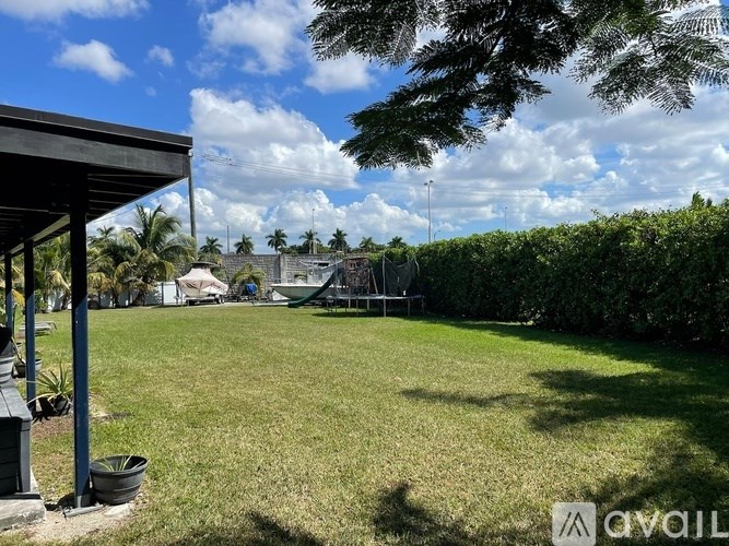 A backyard with a lawn and a covered patio area.