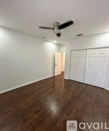 A room with a ceiling fan and wooden flooring.