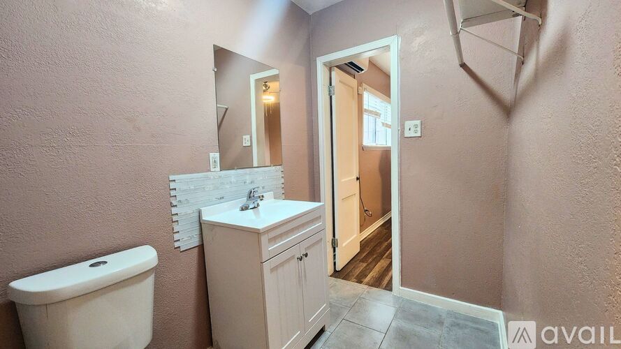 A bathroom with a toilet, sink, and mirror.