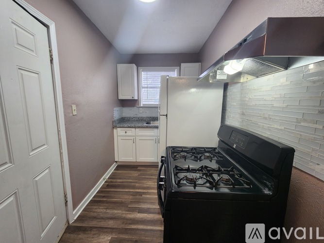 A kitchen with a black stove top oven and a white refrigerator.