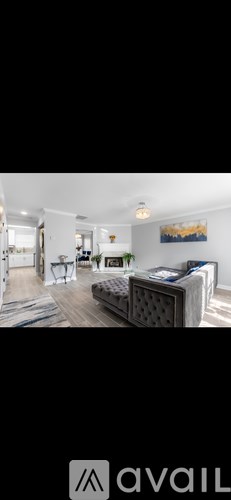 A living room with a grey sofa and a painting on the wall.