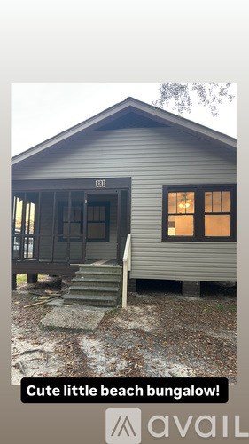 A beach bungalow with a front door and steps leading to it.