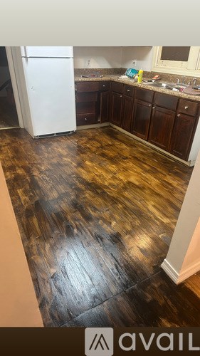 A kitchen with a white fridge and wooden floors.