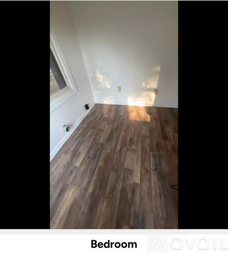 A bedroom with wooden flooring and a window.