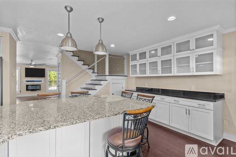 A kitchen with a granite countertop and a staircase in the background.