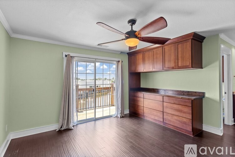 A room with a ceiling fan and a sliding glass door leading to a balcony.