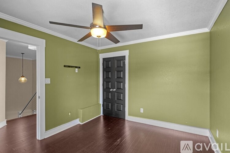 A room with a ceiling fan and a door.