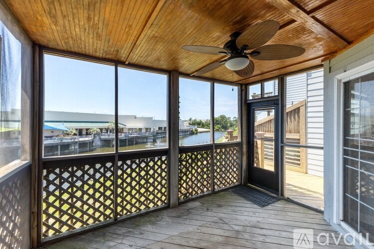 A wooden deck with a ceiling fan and a view of a street.