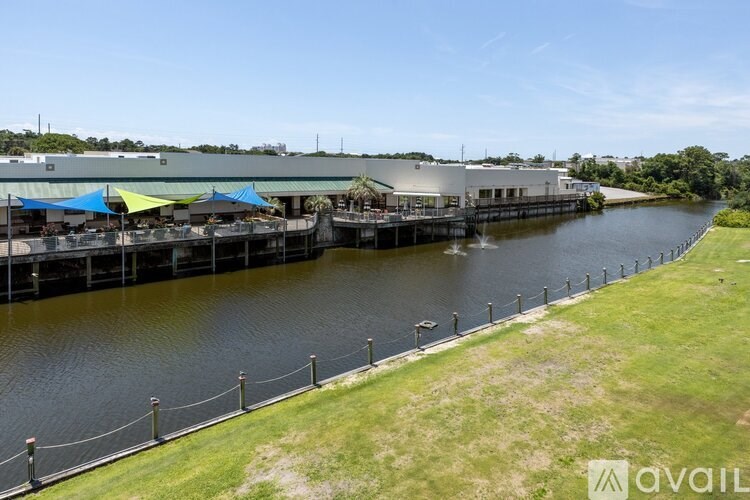 A dock with a building and umbrellas in the background.