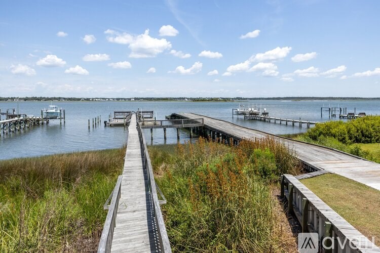 A wooden boardwalk leads to a dock with boats in the water.