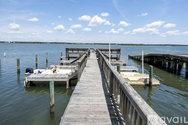 A wooden dock extends into a body of water with boats docked at the end.