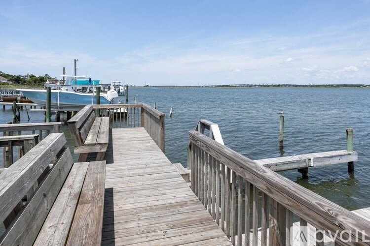 A wooden dock extends into a calm body of water with a boat docked at the end.