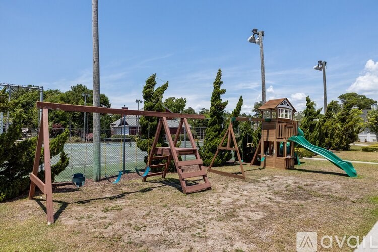 A playground with a green slide and a wooden swing set.