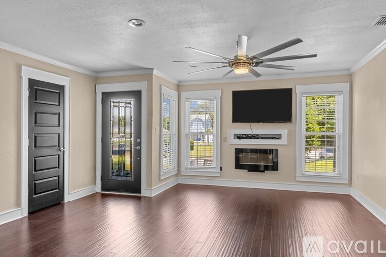 A room with a ceiling fan, a fireplace, and a television.