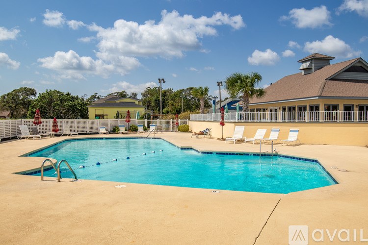 A large swimming pool with a diving board and lounge chairs.