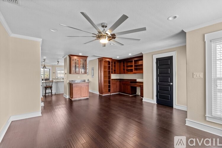 A spacious room with a ceiling fan and wooden flooring.