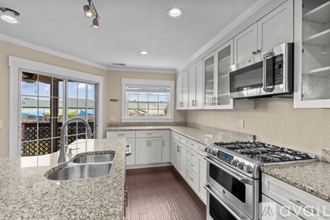 A kitchen with a stove, sink, and microwave.