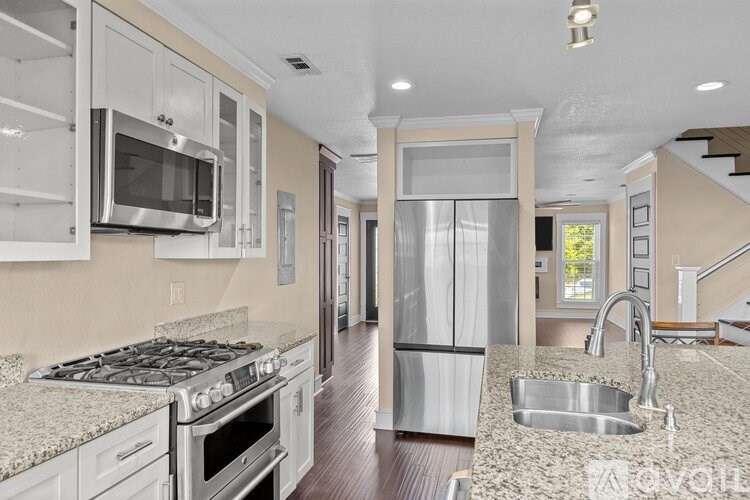 A modern kitchen with stainless steel appliances and a wooden floor.