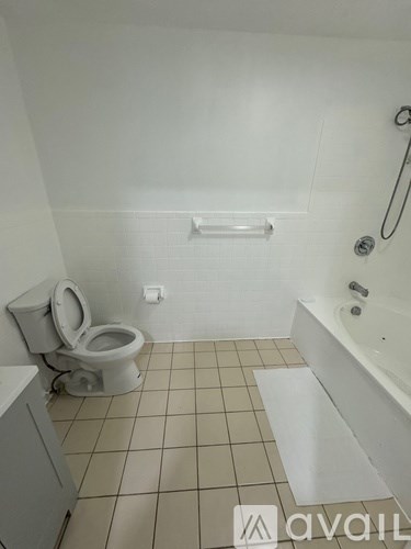 A bathroom with a toilet, tub, and tiled floor.